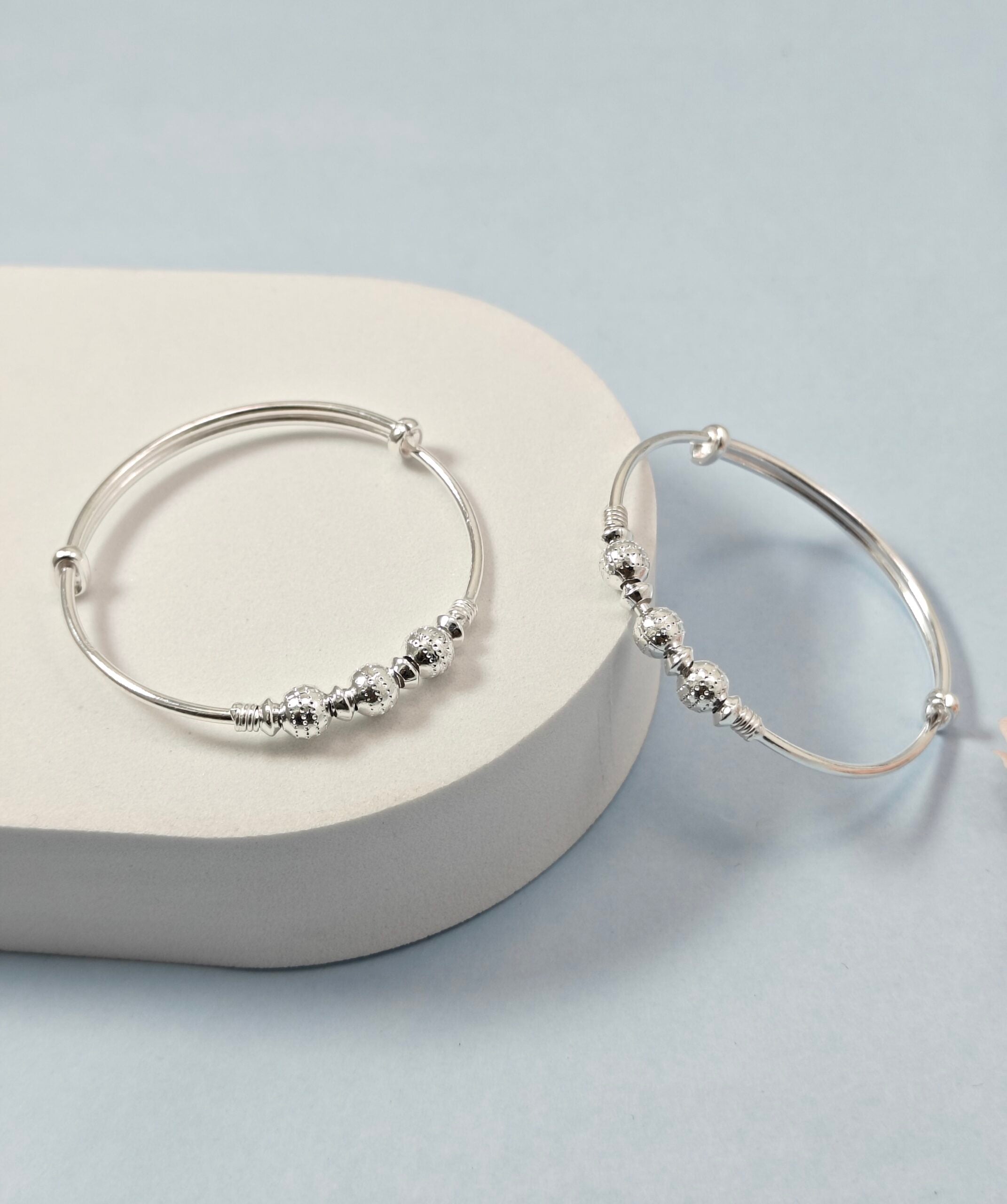 Silver hoop earrings with bead detailing on a light gray surface